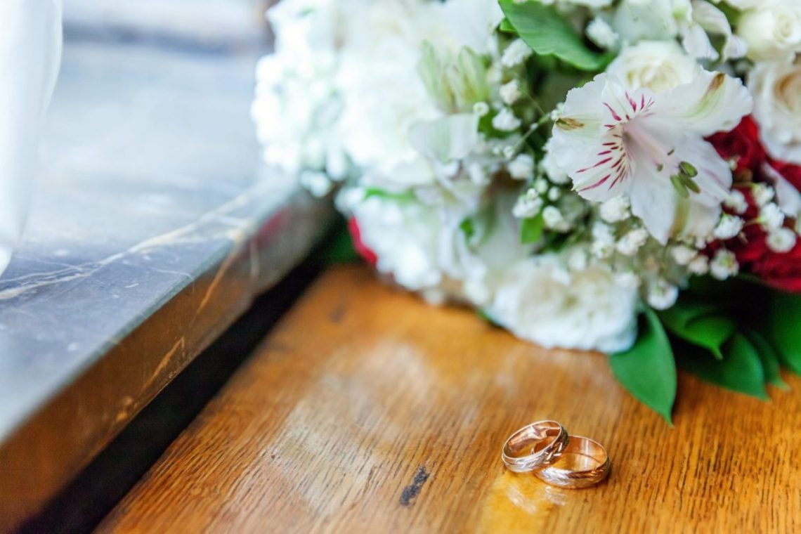 Deux alliances posées côte à côte sur une table en bois, évoquant un mariage supposé.