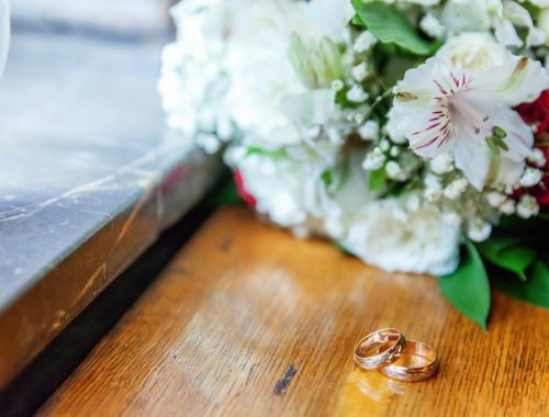 Deux alliances posées côte à côte sur une table en bois, évoquant un mariage supposé.